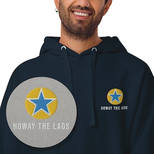 Pode incluir: Hoodie azul marinho com uma estrela amarela e o texto "Howay the Lads" bordado na frente.