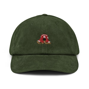 May include: A green corduroy baseball cap featuring an embroidered image of a person wearing a red jersey with the number 6 on it.