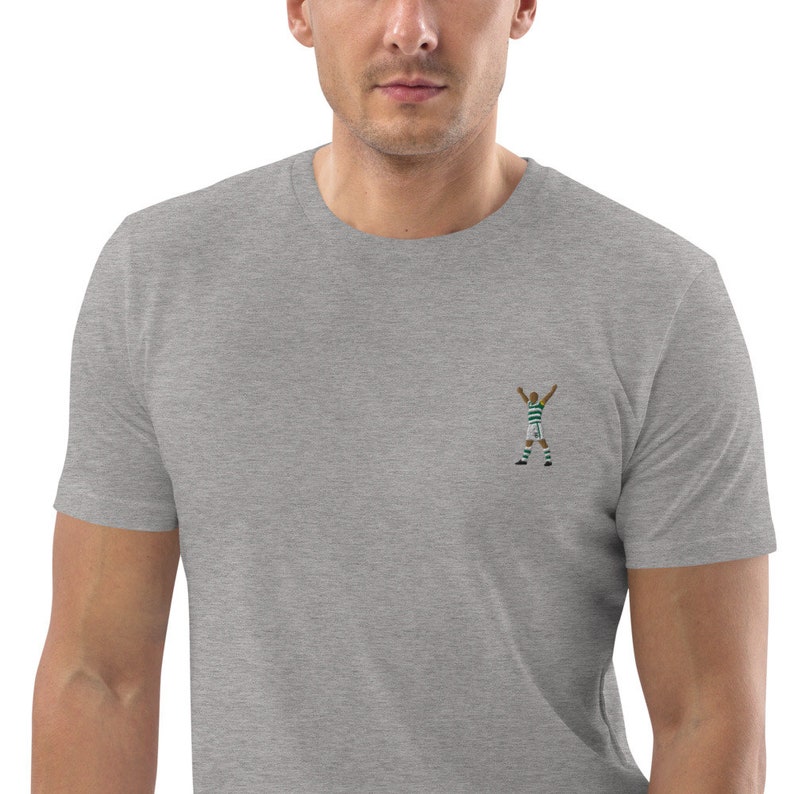May include: A heather gray t-shirt with an embroidered image of a soccer player celebrating a goal.