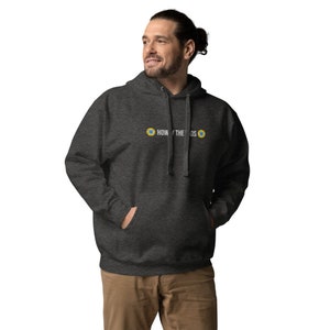 Puede incluir: Una sudadera con capucha gris oscuro con el texto "HOW THE " y dos estrellas amarillas con centros azules.