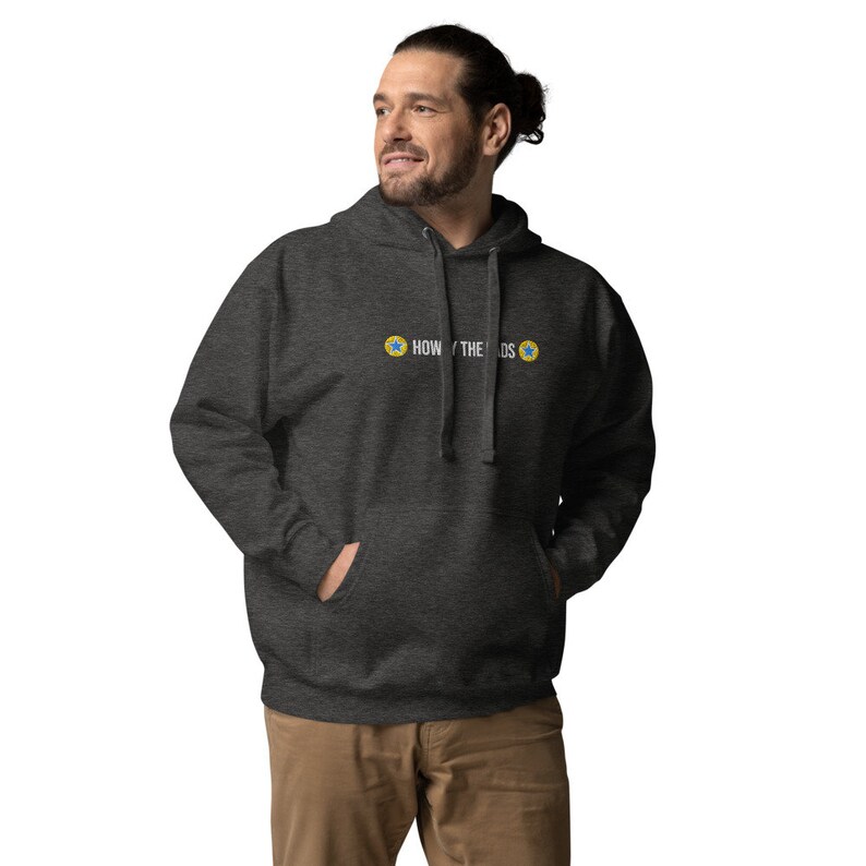 Puede incluir: Una sudadera con capucha gris oscuro con el texto "HOW THE " y dos estrellas amarillas con centros azules.
