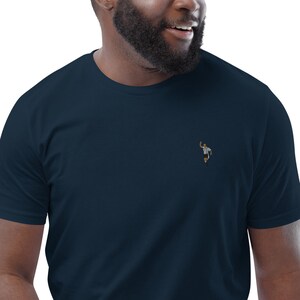 May include: A navy blue t-shirt with a small embroidered image of a referee signaling a touchdown.