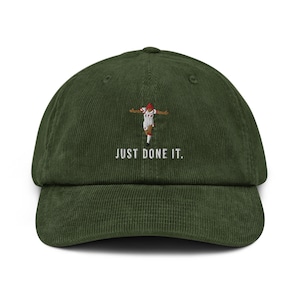 Pode incluir: Um boné de beisebol de veludo cotelê verde com uma imagem bordada de um jogador de futebol com o texto "JUST DONE IT."