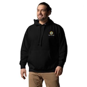 K&ouml;nnte beinhalten: Schwarzer Kapuzenpullover mit einem gelben Kreis und einem blauen Stern auf der linken Brust. Der Text "Know the Code" ist unter dem Grafikdruck.