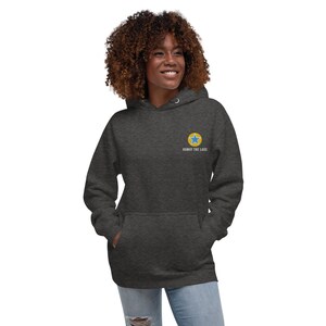 K&ouml;nnte beinhalten: Ein dunkelgrauer Hoodie mit einem gelben Kreis und einem blauen Stern in der Mitte. Der Text "Noway The LACS" steht unter dem Kreis.