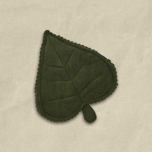 May include: A dark green leaf-shaped decorative item with a textured surface and scalloped edges. The leaf features detailed veining and a small stem. The item is likely made of a soft, plush material, and is set against a neutral background.