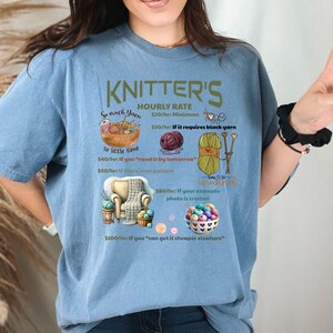 May include: A blue t-shirt with a humorous graphic that reads "Knitter's Hourly Rate" and lists different rates based on the complexity of the knitting project. The graphic includes yarn, knitting needles, and a crocheted item.