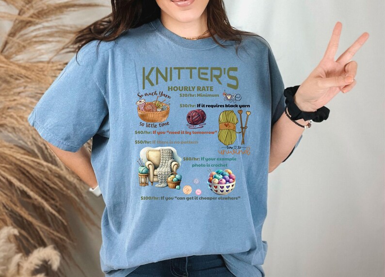 May include: A blue t-shirt with a humorous graphic that reads "Knitter's Hourly Rate" and lists different rates based on the complexity of the knitting project. The graphic includes yarn, knitting needles, and a crocheted item.