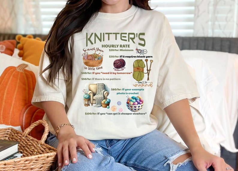 May include: A white t-shirt with a humorous graphic about knitter's hourly rates. The graphic features yarn, knitting needles, and a crochet hook. The text reads "Knitter's Hourly Rate $20/hr: Minimum $30/hr: If it requires black yarn $40/hr: If you "need it by tomorrow" $50/hr: If there is no pattern $80/hr: If your example photo is crochet $100/hr: If you "can get it cheaper elsewhere" Time to unwind"