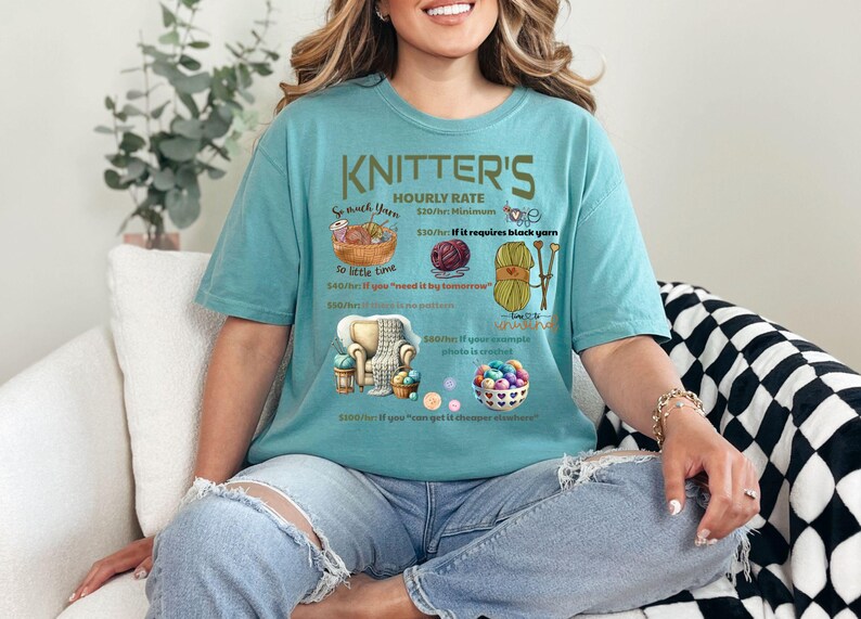 May include: A teal blue t-shirt with a humorous graphic about knitter's hourly rates. The graphic includes yarn, needles, and a chair. The text reads "KNITTER'S HOURLY RATE $20/hr Minimum $30/hr if it requires black yarn $50/hr if you "need it by tomorrow" $100/hr if you can knit it the cheapest and fastest"