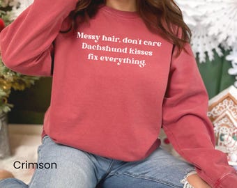 May include: Crimson red sweatshirt with the text "Messy hair, don't care Dachshund kisses fix everything" in white.