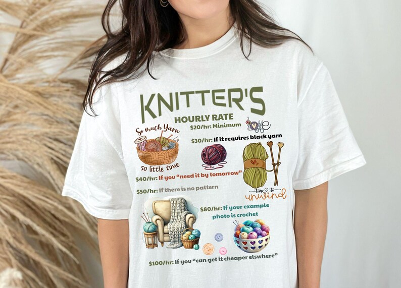 May include: White t-shirt with a green graphic that says "Knitter's Hourly Rate" and lists different prices for knitting projects based on factors like yarn type, time constraints, and pattern availability. The graphic includes illustrations of yarn, knitting needles, and a crocheted item.
