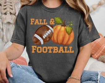 May include: A dark gray t-shirt with the text "Fall & Football" in orange lettering. A brown football and an orange pumpkin are pictured next to the text.