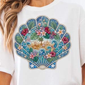 Op de afbeelding: Een wit t-shirt met een grote, gedetailleerde afbeelding van een schelp gevuld met een tropisch strandtafereel. Het ontwerp bevat blauwe oceaangolven, palmbomen, zand, hibiscusbloemen en groen gebladerte, alles met een sprankelende textuur.