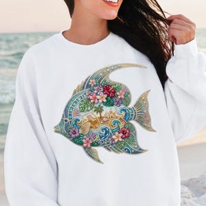 A vibrant digital design of a tropical fish decorated with a faux rhinestone and gemstone texture. The fish features a miniature tropical beach scene with a palm tree, beach chair, and waves, accented by pink hibiscus flowers. Intended for crafts, sublimation and DTF printing.