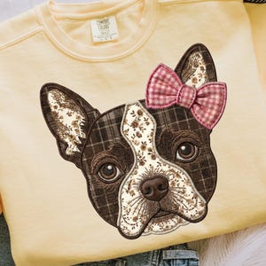 Puede incluir: Sudadera amarilla clara con un gráfico de un perro Boston Terrier. La cara del perro es un mosaico de patrones florales y a cuadros, con un lazo rosa a cuadros. La sudadera tiene una etiqueta Comfort Colors.