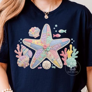 May include: A navy blue t-shirt featuring a central graphic of a large starfish composed of various pastel-colored patchwork patterns, surrounded by illustrations of seashells, coral, small fish, and a sand dollar, with the text BLUE DOG SVG.