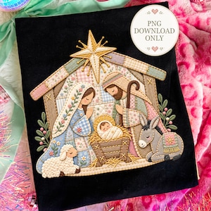 May include: A black fabric surface featuring an embroidered nativity scene with a gold star above a stable. The design includes figures of a person, another person, a baby in a manger, a sheep, and a donkey, all decorated with pastel floral patterns.