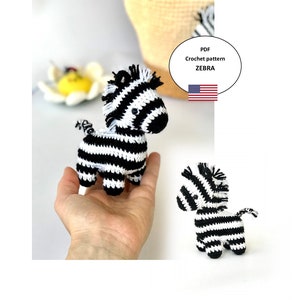 May include: A crochet pattern for a black and white zebra amigurumi toy. The pattern is available as a PDF download. The image shows two finished zebra toys.