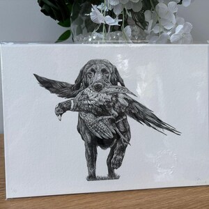 K&ouml;nnte beinhalten: Schwarz-Wei&szlig;-Zeichnung eines Hundes, der einen Vogel tr&auml;gt. Der Hund, wahrscheinlich ein Retriever, ist in Bewegung dargestellt. Das Kunstwerk f&auml;ngt die Textur des Fells des Hundes und des Gefieders des Vogels vor wei&szlig;em Hintergrund ein.