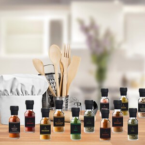 May include: A selection of spice jars with black lids and labels, displayed on a wooden surface. A chef's hat, wooden spoons, a fork, a spatula, and a grater are in the background. The jars contain various spices, including Jamaican jerk seasoning and thyme.