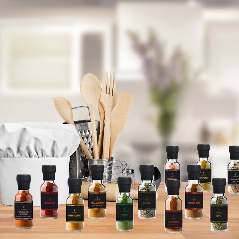 May include: A selection of spice jars with black lids and labels, displayed on a wooden surface. A chef's hat, wooden spoons, a fork, a spatula, and a grater are in the background. The jars contain various spices, including Jamaican jerk seasoning and thyme.