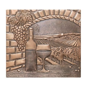 May include: A copper-colored metal wall art piece depicting a wine bottle, a glass of wine, and a grapevine. The background shows a vineyard with rolling hills.