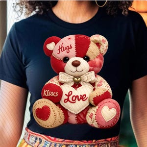 Könnte beinhalten: Ein Teddybär mit Patchwork-Design in Rot-, Rosa- und Beigetönen. Der Bär hält ein herzförmiges Kissen mit dem Wort "Love" und einer Schleife. Auf dem Kopf steht "Hugs" und auf dem Fuß "Kisses".