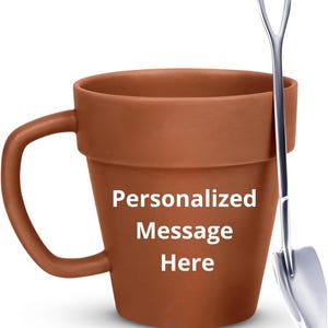May include: A brown ceramic mug shaped like a flower pot, with a handle and the text "Personalized Message Here" in white. A small silver trowel rests against the mug. The mug is designed for gardening enthusiasts.
