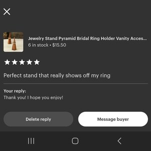 May include: A close-up of three small, pyramid-shaped jewelry stands made of a dark wood. The stands are designed to hold rings. The image is from an Etsy listing, with a customer review and seller's reply.