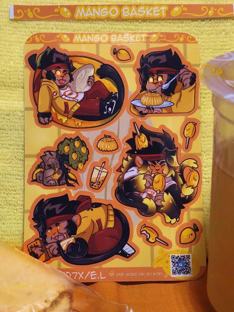May include: A set of six stickers featuring cartoon monkeys enjoying mango-themed treats. The stickers are yellow, orange, and brown with black outlines. The text "Mango Basket" appears twice on the stickers. A QR code is included on the bottom right corner of the sticker sheet.