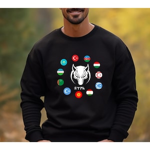 Op de afbeelding: Zwart sweatshirt met een witte wolf-afbeelding en een cirkel van vlaggen die de Turkse landen vertegenwoordigen. De tekst "RTYNH" staat onder de wolf.