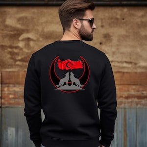 Op de afbeelding: Zwart sweatshirt met een rood halve maan en ster ontwerp. Het ontwerp bevat ook een silhouet van Turkije en twee wolven die naar de maan huilen.