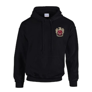 Op de afbeelding: Zwart hoodie met een geborduurd wapenschild in goud en rood met een halve maan en een ster.