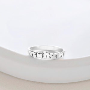 May include: A silver ring with the word "madison" engraved on it.