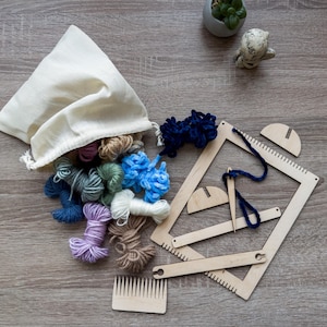 May include: A craft kit with a variety of colorful yarn skeins spilling from a canvas bag. The kit includes a wooden weaving loom, a comb, and other wooden tools. The yarn colors include blue, green, purple, and brown.