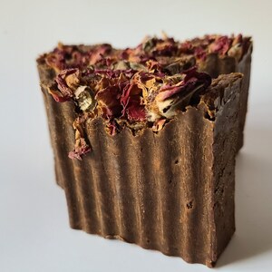 May include: A brown bar of soap with dried rose petals on top. The soap has a textured surface.