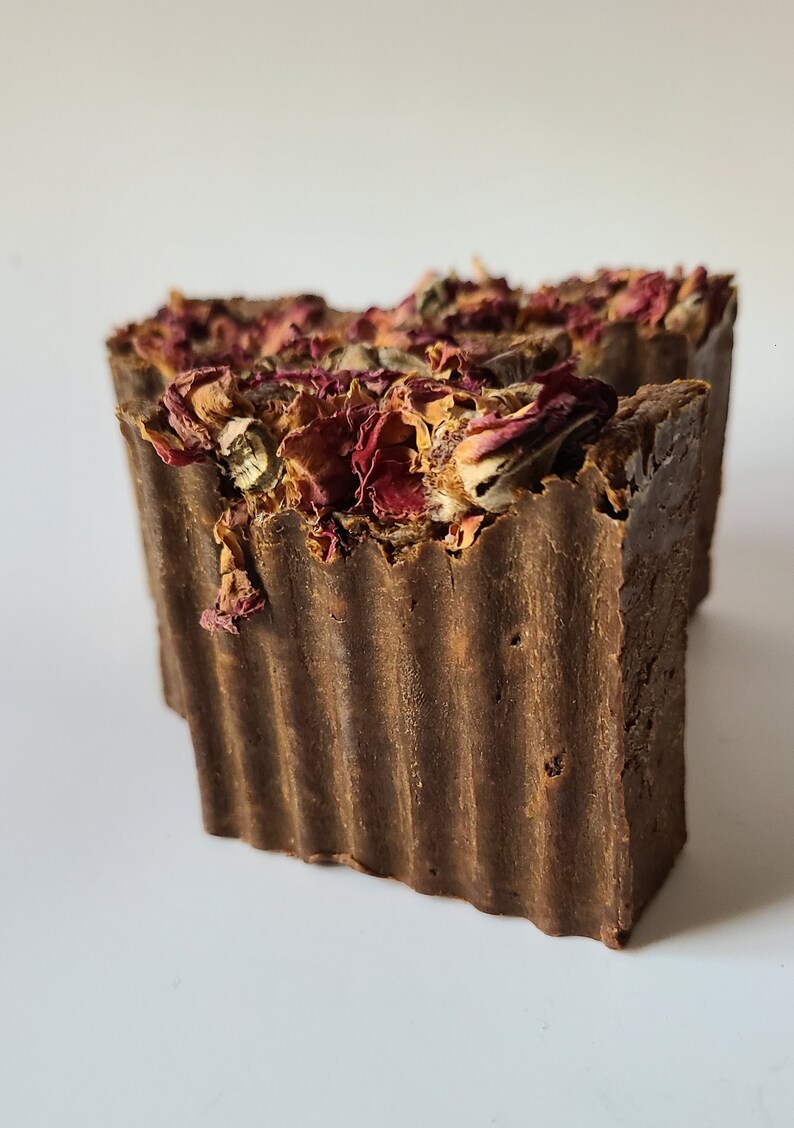 May include: A brown bar of soap with dried rose petals on top. The soap has a textured surface.