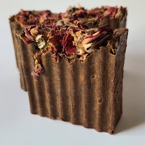 May include: A brown bar of soap with dried rose petals on top. The soap has a ridged texture.