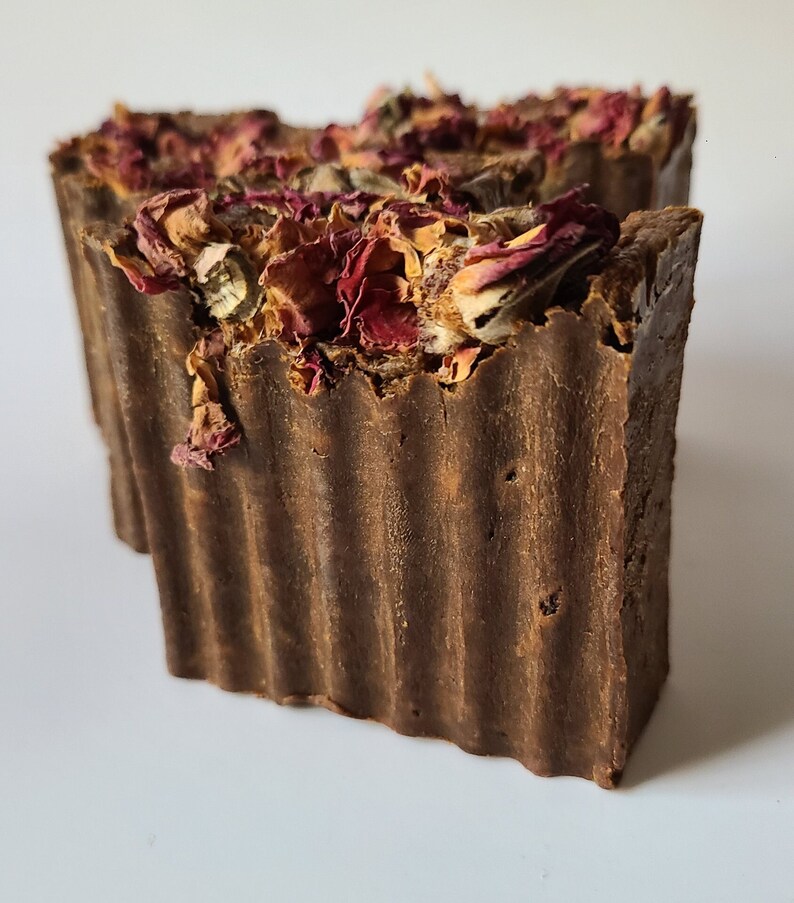 May include: A brown bar of soap with dried rose petals on top. The soap has a ridged texture.