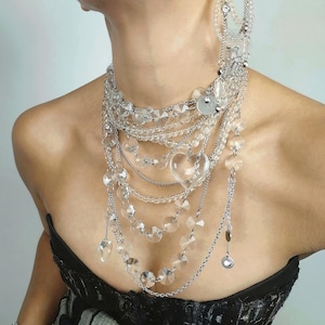 Multi-strand clear quartz necklace with layered stainless steel chains and crystal heart pendants worn by a model.