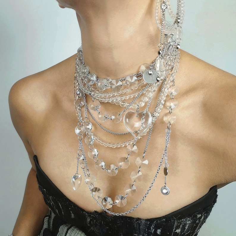 Multi-strand clear quartz necklace with layered stainless steel chains and crystal heart pendants worn by a model.