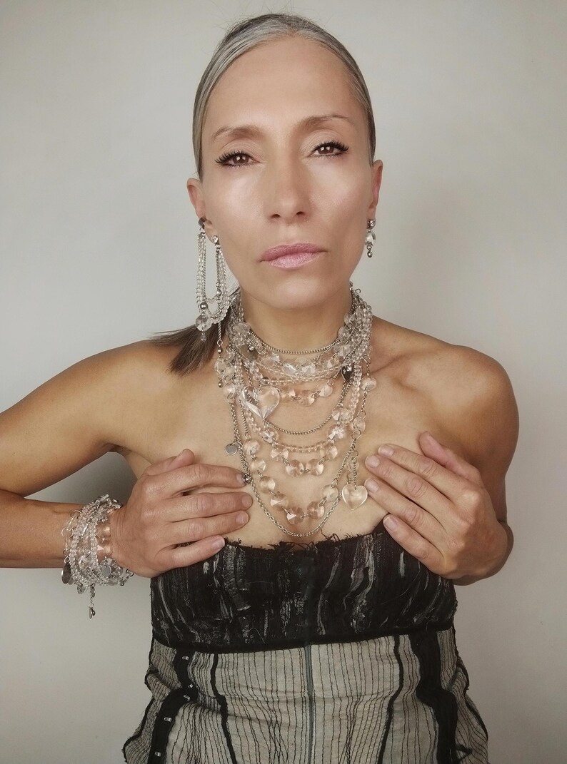 Clear quartz jewelry set including multi-row necklace, bracelets, and earrings for a complete statement look.
​Clear quartz statement jewelry set full look on a model featuring all layered pieces and crystal heart accents.