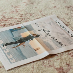 May include: A newspaper announcement with the headline "Save the Date Press" and the text "we're getting married!"  The date "9.23.23" is printed in large, bold font. A photo of a couple embracing is in the background.