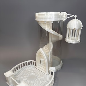 Puede incluir: Torre blanca impresa en 3D con una escalera de caracol dentro de un cilindro transparente. La torre tiene un balcón con una barandilla y un pequeño cenador colgando de la parte superior.