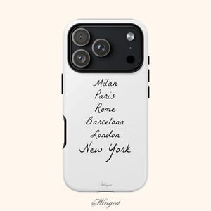 May include: White phone case with a black camera module and the names of cities: Milan, Paris, Rome, Barcelona, London, and New York in a handwritten font. The brand name "Winged" is at the bottom.
