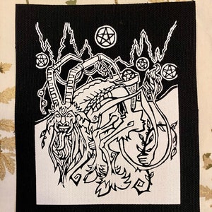 May include: Black and white embroidered patch with a detailed illustration of a horned creature with a pentagram above it. The creature is surrounded by vines and other plant life. The patch has a black border and is made of fabric.