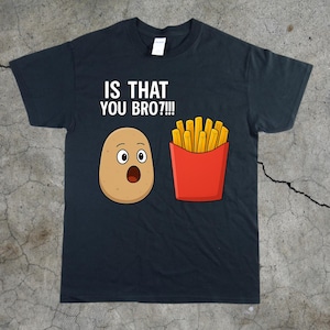 Puede incluir: Camiseta negra con la frase "IS THAT YOU BRO?!!!" encima de una patata de dibujos animados con expresión de sorpresa y una caja roja de patatas fritas. La patata y las patatas fritas son de estilo cartoon.