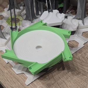 Può includere: Una pista circolare bianca con un pezzo di pista verde attaccato. Il pezzo di pista è in plastica e ha una superficie liscia.