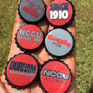 Peut inclure: Six capsules de bouteille circulaires à bords dentelés noirs, arborant des motifs rouges et gris. Le texte comprend : Pretty Girls Choose NCCU, SINCE 1910, NCCU MADE ME, Eagle Pride, DURHAM MADE ME et NCCU ALUMNI, en lettres grasses et nettes.